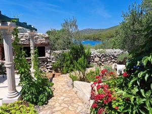 a garden with flowers and a building and a lake at House Murtelica in Tkon