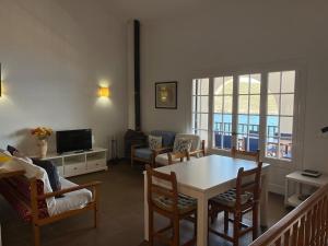 ein Wohnzimmer mit Tisch und Stühlen und einem Fernseher in der Unterkunft ES FAR AZUL by SOM Menorca in Fornells