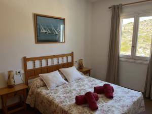 ein Schlafzimmer mit einem Bett mit zwei roten Handtüchern darauf in der Unterkunft ES FAR AZUL by SOM Menorca in Fornells