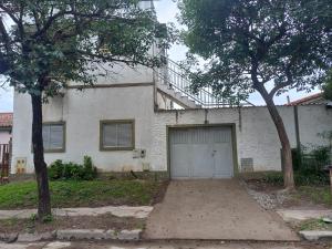 ein weißes Haus mit einer Garage und zwei Bäumen in der Unterkunft America in San Miguel de Tucumán