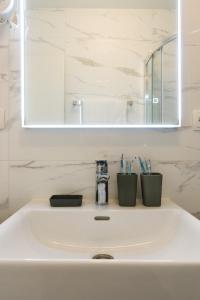 a bathroom sink with two cups and a mirror at Paradise found in Komiža +31 photos
