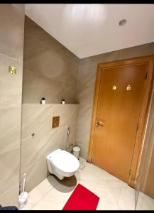 a bathroom with a toilet and a wooden door at Amman studio Damac Tower in Amman