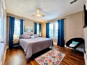 a bedroom with a bed with blue curtains and a chair at Charming house in Memphis in Memphis