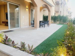 a patio with grass and chairs in a building at شقة فندقية فى الشيخ زايد داخل كمبوند حديقة خاصة ومدخل خاص in Sheikh Zayed