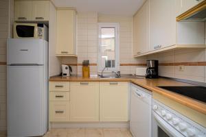 a kitchen with white cabinets and a white refrigerator at Estrella 243A in L’Alfàs del Pi