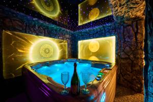 a jacuzzi tub with two glasses and a bottle of wine at Sianisia Adults Only & Private Spa in Haţeg