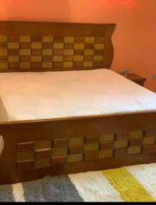 a bed with a wooden headboard with a white mattress at Chez awa in Saint-Louis +5 photos