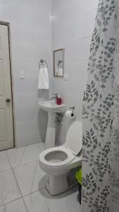 a white bathroom with a toilet and a sink at La Paloma Hostal in Moyogalpa
