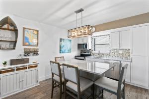 a kitchen with white cabinets and a table and chairs at Anglers Cove Unit J205 in Marco Island