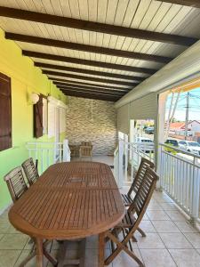 Una mesa y sillas de madera en un patio. en Jolie maison saisonnière en Guadeloupe de 160m2 disposant de 4 chambres 2 toilettes une grande véranda et terrasse, en Vieux-Fort