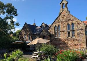 an old brick building with an umbrella in front of it at St Hilda Beach Hut Alnmouth in Alnmouth