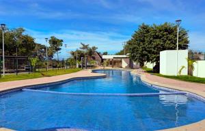 a swimming pool with blue water in a park at Departamento en coto con alberca y seguridad 24-7 in Ixtapa