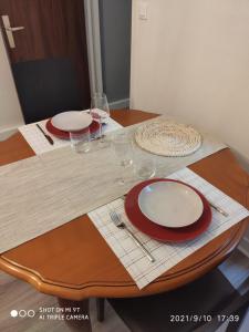 a table with red and white plates and wine glasses at Du Guesclin Appart in Saint-Brieuc +2 photos