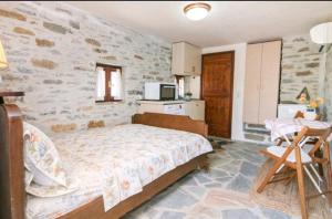 a bedroom with a bed and a stone wall at Πέτρινο in Tinos