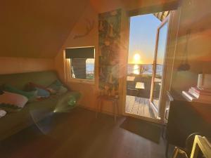 een persoon die op een bank ligt in een kamer met een raam bij St Oswald Beach Hut Alnmouth in Alnmouth