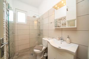 a white bathroom with a sink and a toilet at Dendra Apartments at Skala in Poros