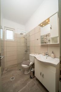 a bathroom with a toilet and a sink and a mirror at Dendra Apartments at Skala in Poros