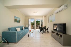 a living room with a blue couch and a television at Dendra Apartments at Skala in Poros