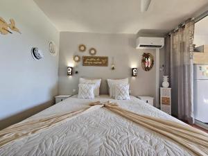 une chambre avec un grand lit avec des draps et des oreillers blancs dans l'établissement L'oiseau du Paradis vue mer Studio a Saint Francois a 100 m de la plage, à Saint-François 28 autres photos