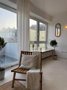 a living room with a chair and a large window at Penthouse mit Loftcharakter - Parkplatz, Fahrstuhl & Balkon in Kiel +18 photos