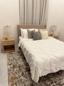 a bedroom with a large white bed with two night stands at City Abode Kingston Jamaica in Kingston