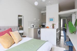 een witte slaapkamer met een bed en een keuken bij Stylish Studio in the Heart of Kallio in Helsinki