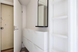 een witte badkamer met een spiegel aan de muur bij Stylish Studio in the Heart of Kallio in Helsinki +18 foto's