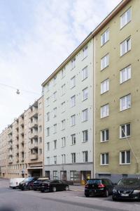 een groot gebouw met auto's ervoor geparkeerd bij Stylish Studio in the Heart of Kallio in Helsinki