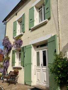 a building with green shutters and a door and a bench at Le Charme du Perigord - chambre & table d'hotes in Saint-Sulpice-dʼExcideuil