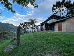 a house on a hill with a grass yard at CASA DE VIDRO Na Mantiqueira in Dias