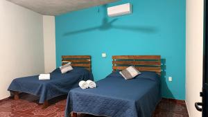 two beds in a room with blue walls at Casa Mar Zicatela in Puerto Escondido