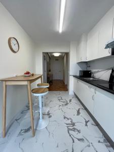 a kitchen with white cabinets and a table and stool at Otto's Home Horizonte in Lastres