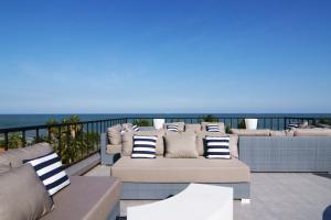 a patio with couches and the ocean in the background at Dune Hua Hin Hotel in Hua Hin