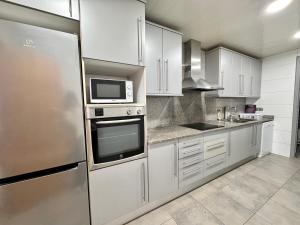 a kitchen with white cabinets and a stainless steel refrigerator at Apt compartido martirrena in Badalona
