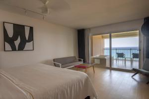 una camera da letto con un letto, un divano e un balcone di Fiesta Americana Cozumel All Inclusive a Cozumel
