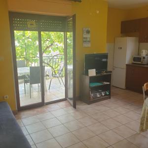 a living room with a television and a kitchen with a patio at Rajčić Apartmani in Omiš