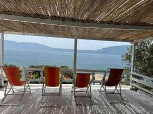 two chairs and an umbrella on a deck with the ocean at Mario Rooms in Vlorë