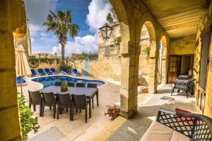 een terras met een tafel en stoelen naast een zwembad bij Caqsi Farmhouse in Kerċem