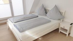 Una cama blanca con dos almohadas encima. en Ferienhaus Andy Kellenhusen - 6 Personen 3 Schlafzimmer 4, en Kellenhusen