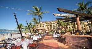 un restaurante con mesas y sillas y un edificio en 2BD Oceanview Suite Villa del Palmar Flamingos, en Nuevo Vallarta 
