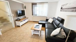 Una sala de estar con un sofá de cuero negro y un televisor. en Ferienhaus Angela Kellenhusen - 6 Personen 3 Schlafzimmer 4, en Kellenhusen