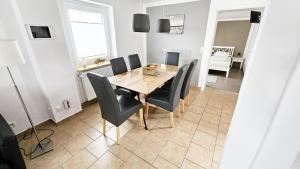 Un comedor con mesa y sillas de madera. en Ferienhaus Angela Kellenhusen - 6 Personen 3 Schlafzimmer 4, en Kellenhusen