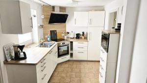 Una cocina con gabinetes blancos y piso de baldosas. en Ferienhaus Angela Kellenhusen - 6 Personen 3 Schlafzimmer 4, en Kellenhusen 20 fotos más