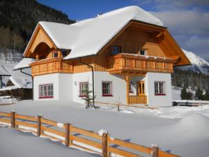 ein schneebedecktes Haus mit einem Zaun in der Unterkunft Ferienhaus Longa in Weisspriach