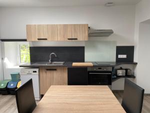 a kitchen with a wooden table with chairs and a sink at Appartement 4 personnes in Parthenay
