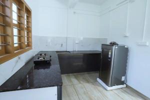 a kitchen with a black counter and a refrigerator at bethel apartments teekoy in Erāttupetta +1 photo