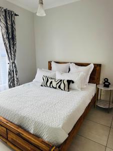 a bed with white sheets and zebra pillows at 126Theblyde in Pretoria +9 photos