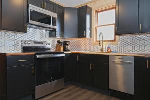 a kitchen with black cabinets and stainless steel appliances at Private Hot tub new 2 Bedroom Home in Catskills in Elka Park +10 photos