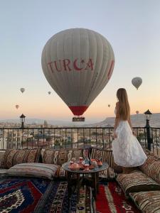 a woman standing on a couch looking at a hot air balloon at Kismet Cave Mansion in Göreme