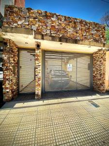 two garage doors in a building with a stone wall at LU DORMIS Alquiler Temporario in Corrientes